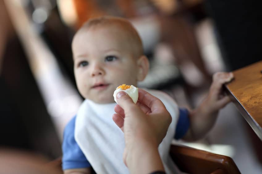 Toddler eating boiled egg in the restaurant
