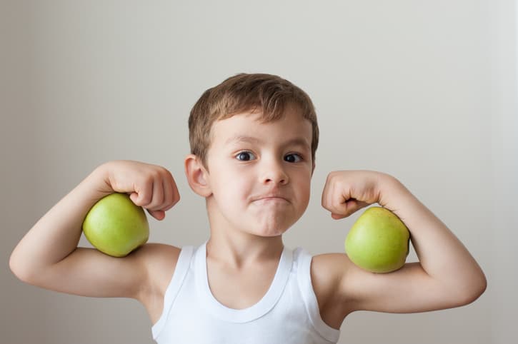 boy with green apples showing biceps face