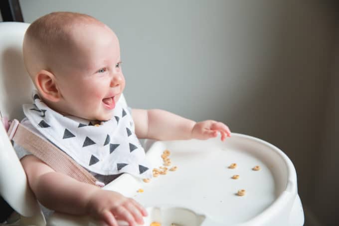 happy baby with food on a high chair