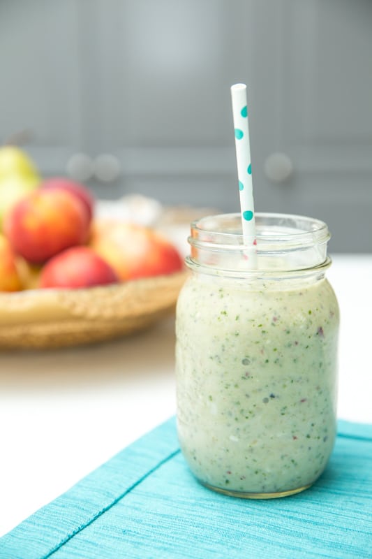 green smoothie in a mason jar with a paper straw
