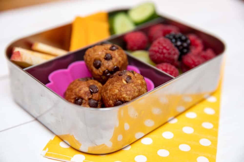 healthy chocolate chip pumpkin energy bites sitting in a bento box with other snacks