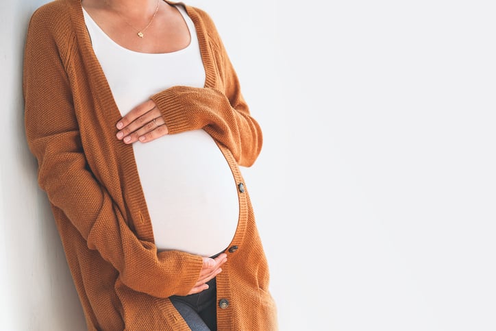 pregnant woman wearing a white shirt holding her stomach