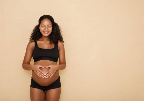 Pregnant woman holding hands on her belly making a heart symbol