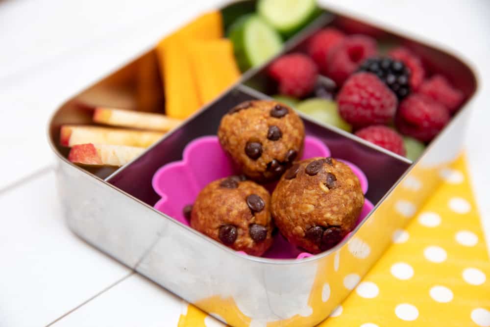 pumpkin chocolate chip energy bites in a lunch box with fruits and vegetables