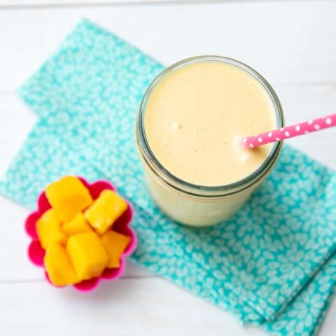 mango coconut banana smoothie in a jar with mango cubes