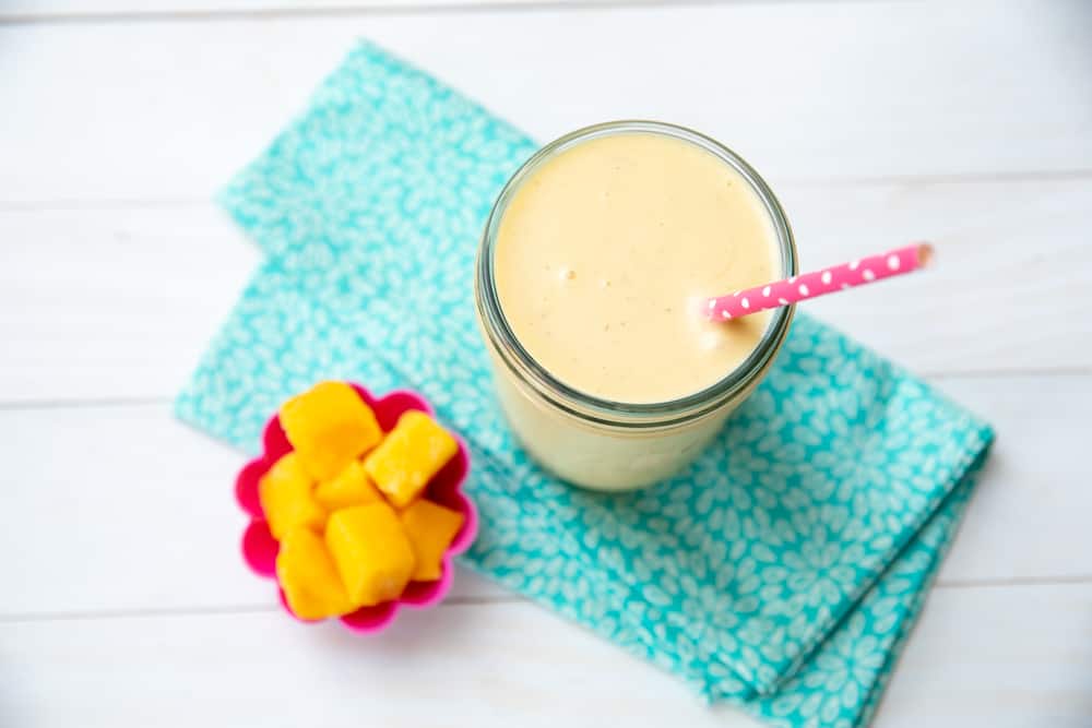 mango coconut banana smoothie in a jar with mango cubes