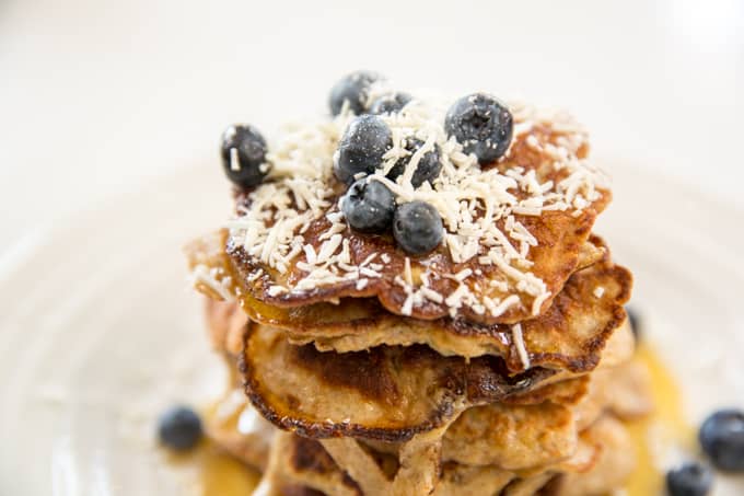 stack of pancakes with blueberries coconut and maple syrup