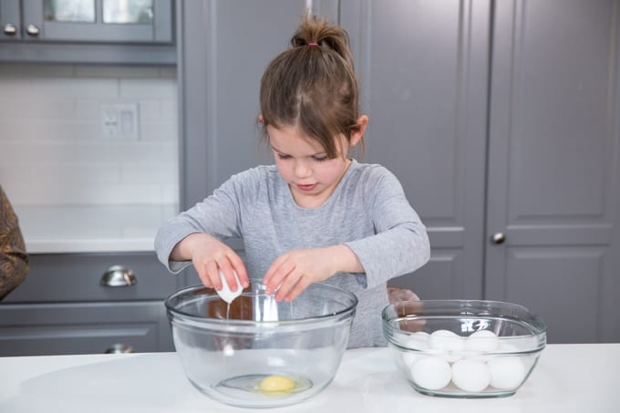 young child cracking eggs into a bowl