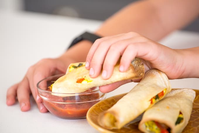 child dipping taquitos in salsa