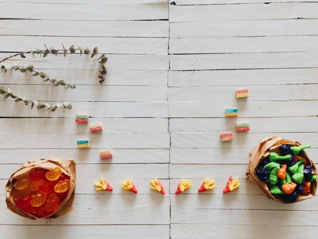 gummy Halloween candy in paper bags on a wooden floor