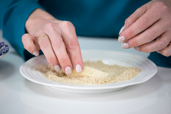 Variety of soft finger foods being mixed into infant cereal by adults hands.