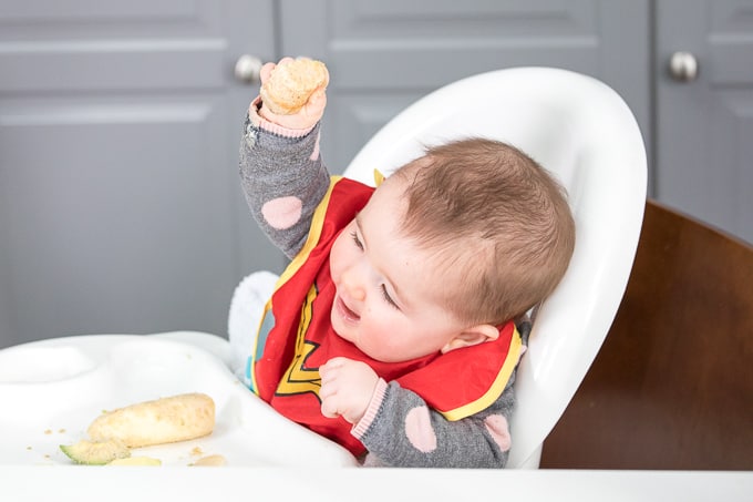 baby in high chair learning how to self feed