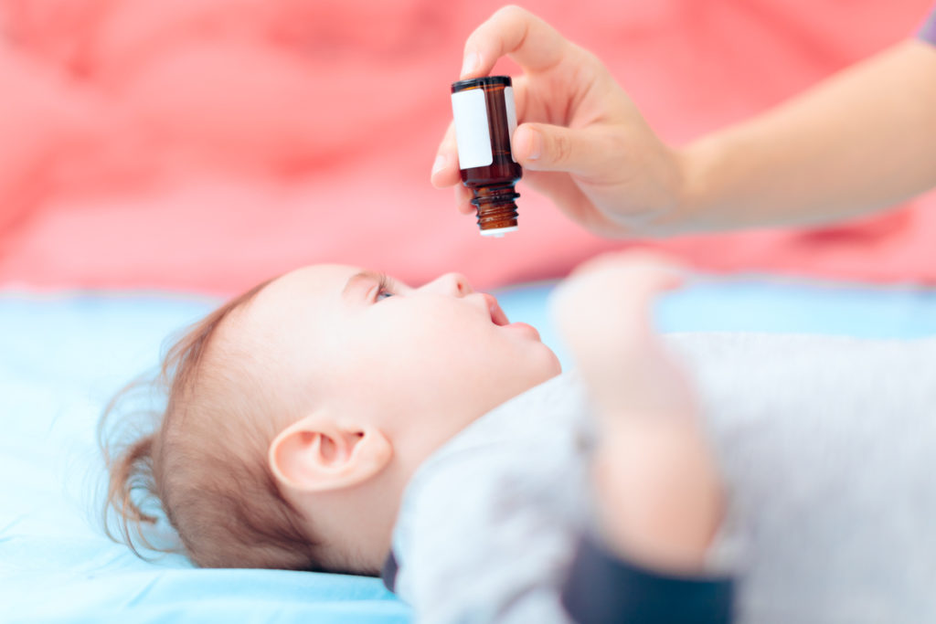 baby on a changing table receiving vitamin D drops