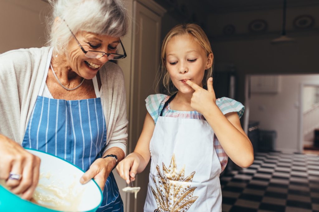 grandmother and granddaughter baking a cake together