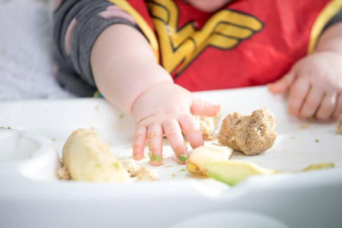 baby hands covered in food while learning how to eat solids