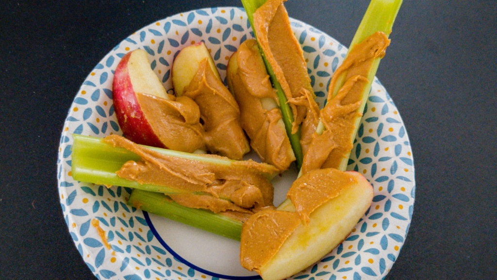 a bunch of celery and apples spread with peanut butter