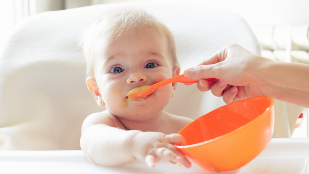 close up of a baby being spoon fed purees