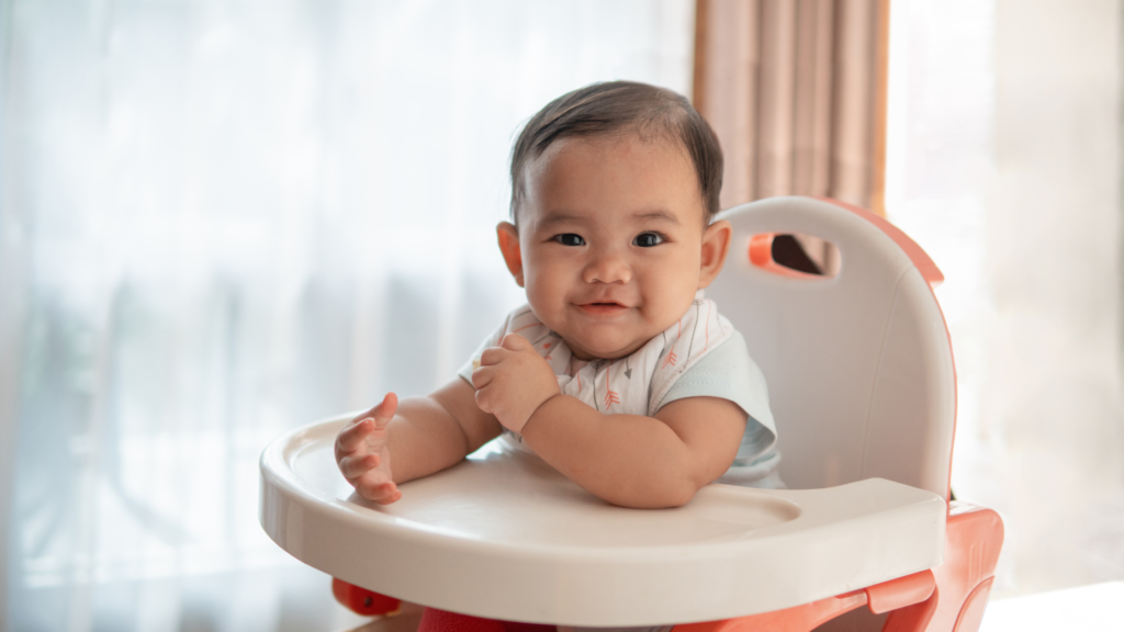 a cute baby looking at the camera while sitting in a highchair
