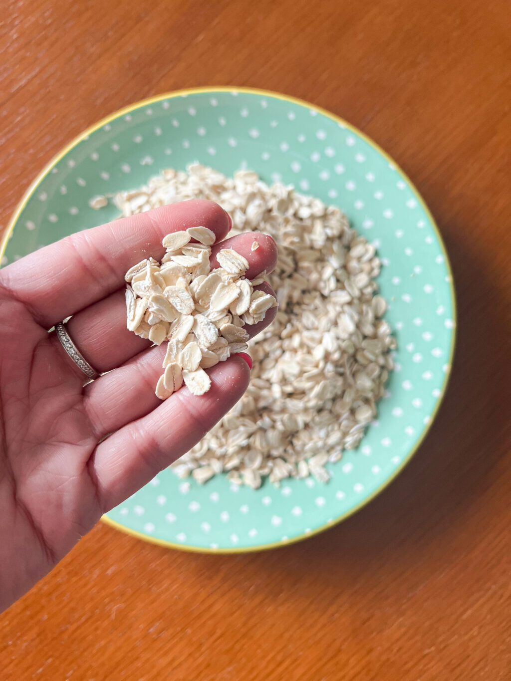 rolled oats on a plate with hand picking some up
