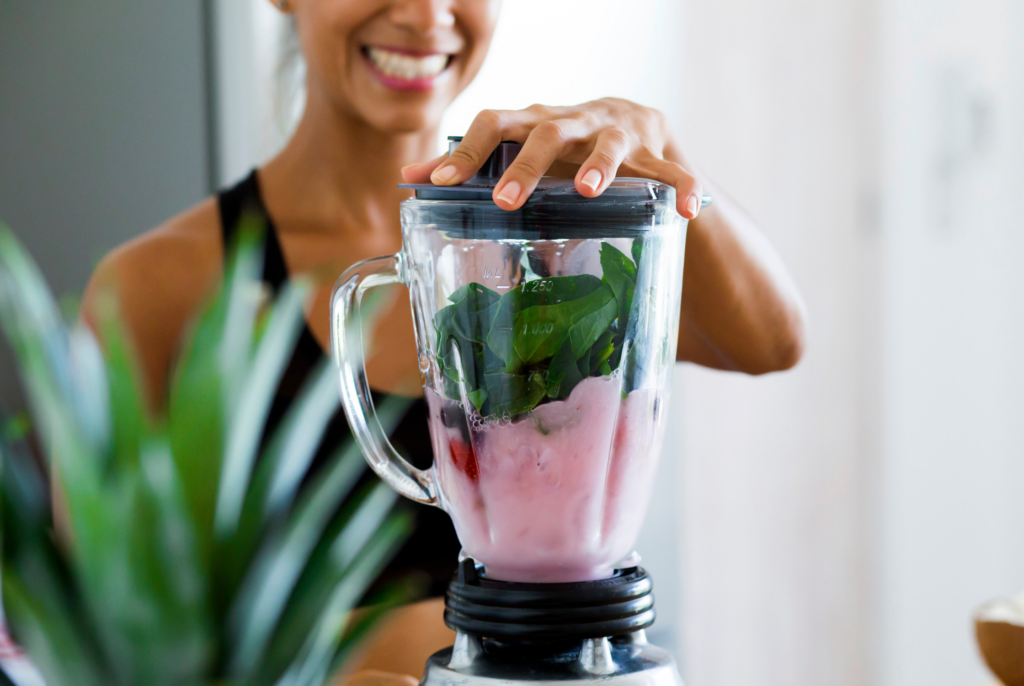 close up of a woman making a smoothie in a blender