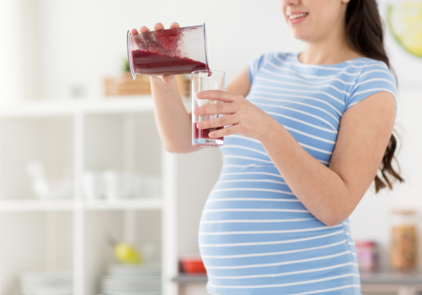 close up of a pregnant woman holding a smoothie in a glass