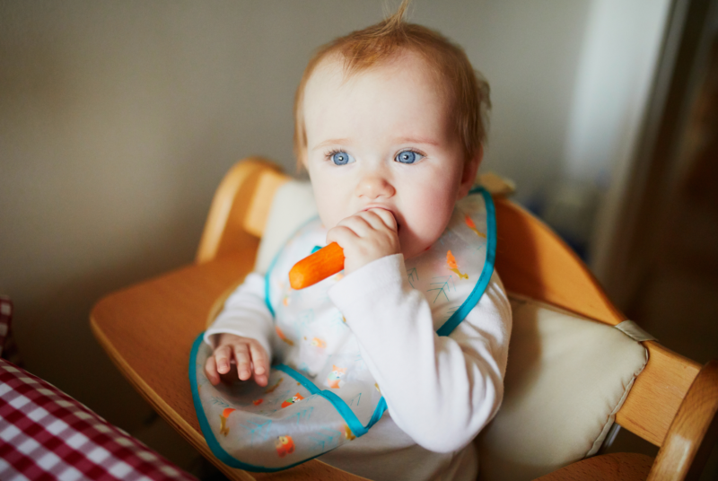 close up of a baby practicing baby led weaning with carrots