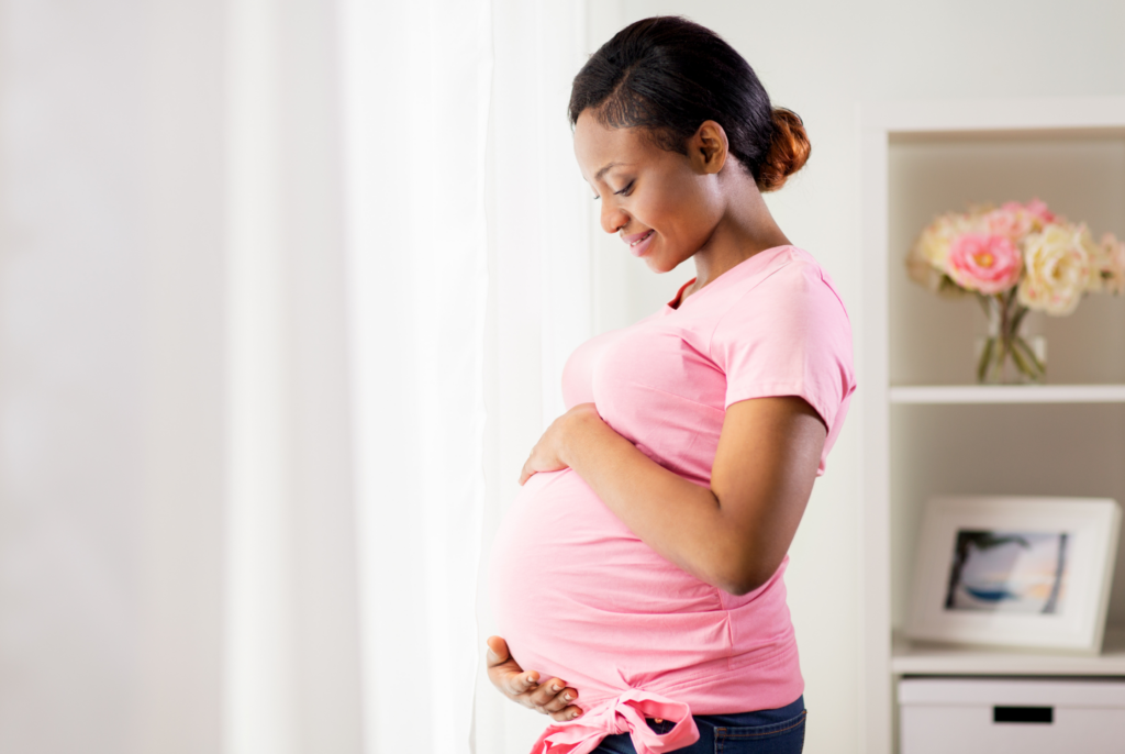 a Black pregnant woman holding her stomach