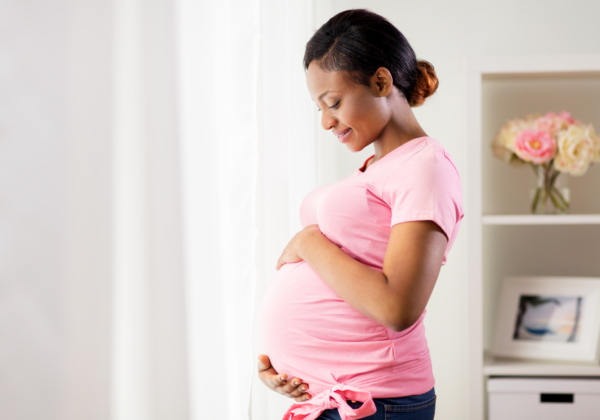 a Black pregnant woman holding her stomach