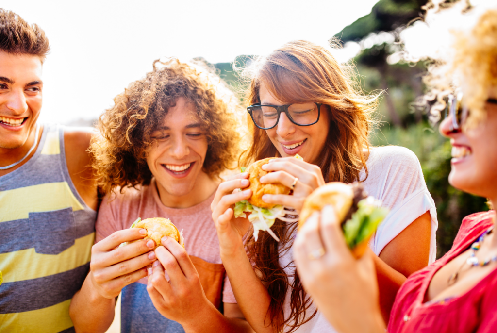 close up of teens enjoying sandwiches together in a circle