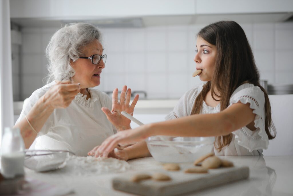 side view of a grandmother and a tween enjoying baking together