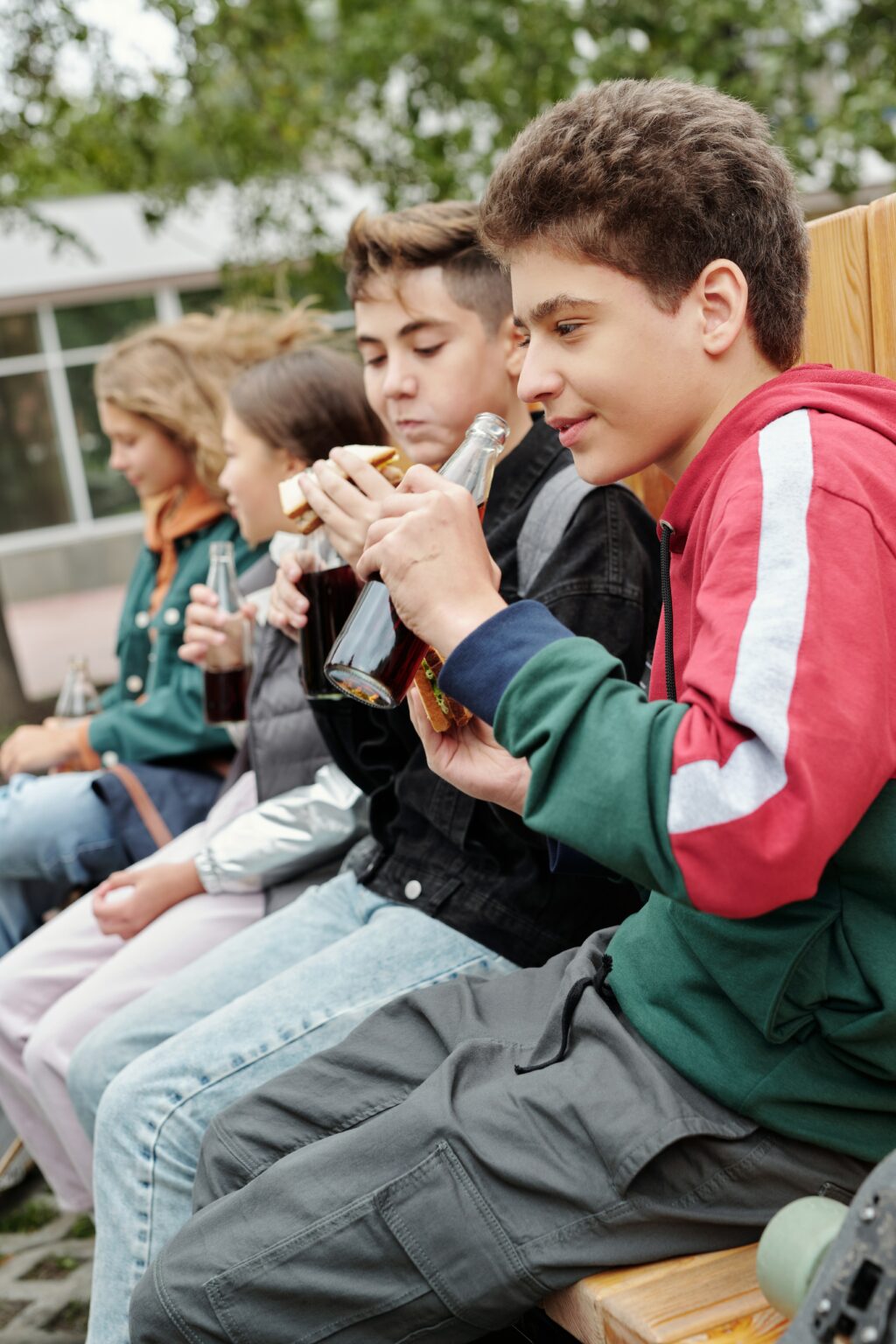 side view of young tweens enjoying their lunches together while drink soda pop