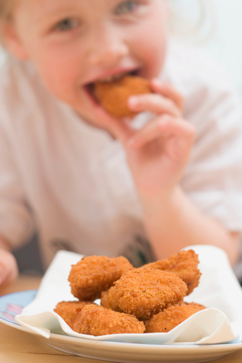 close up of a child eating chicken nuggets
