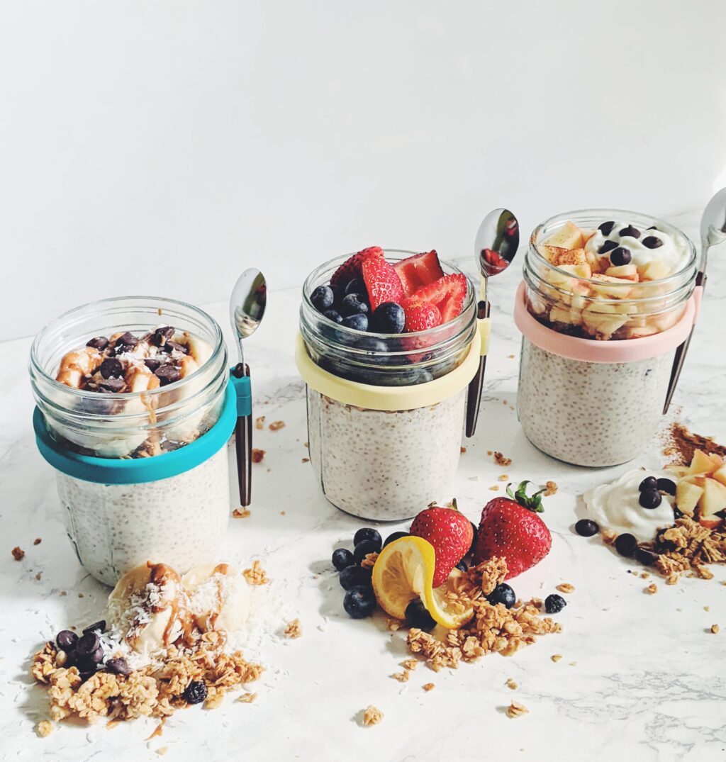 chia pudding in cute containers with spoons topped with fruit and granola