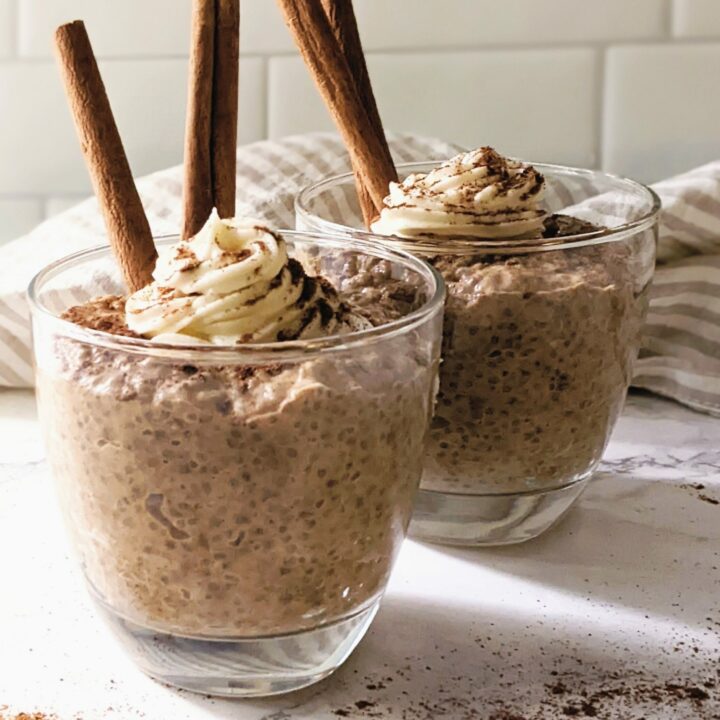 side view of pumpkin pie chia pudding in glass mugs with cinnamon sticks