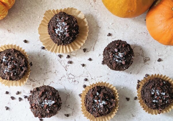 top down view of double chocolate pumpkin muffins on a marble surface with pumpkins in the background