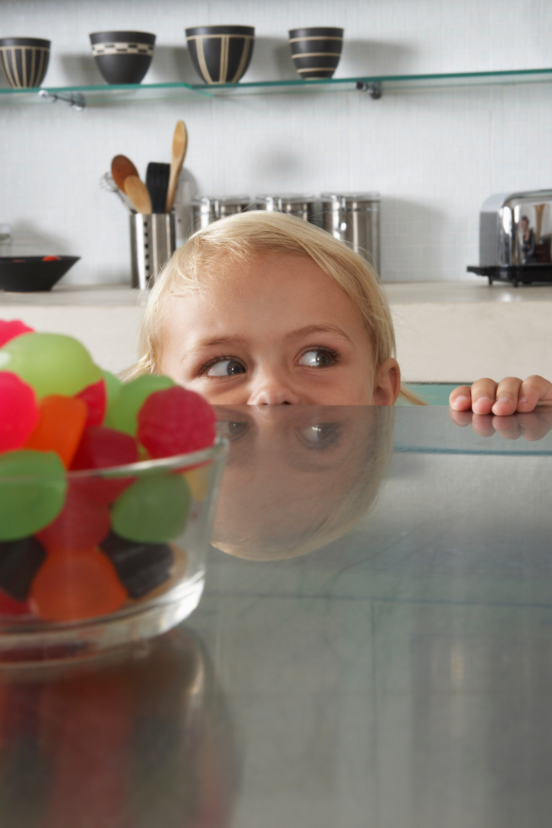 close up of a child attempting to sneak candy off a counter top