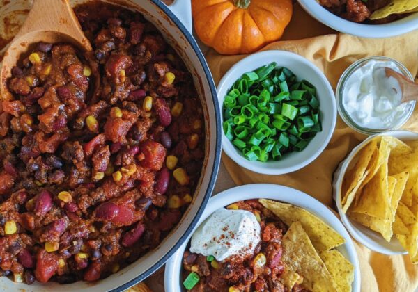 top down view of pumpkin turkey chili in bowls with tortilla chips and garnishes