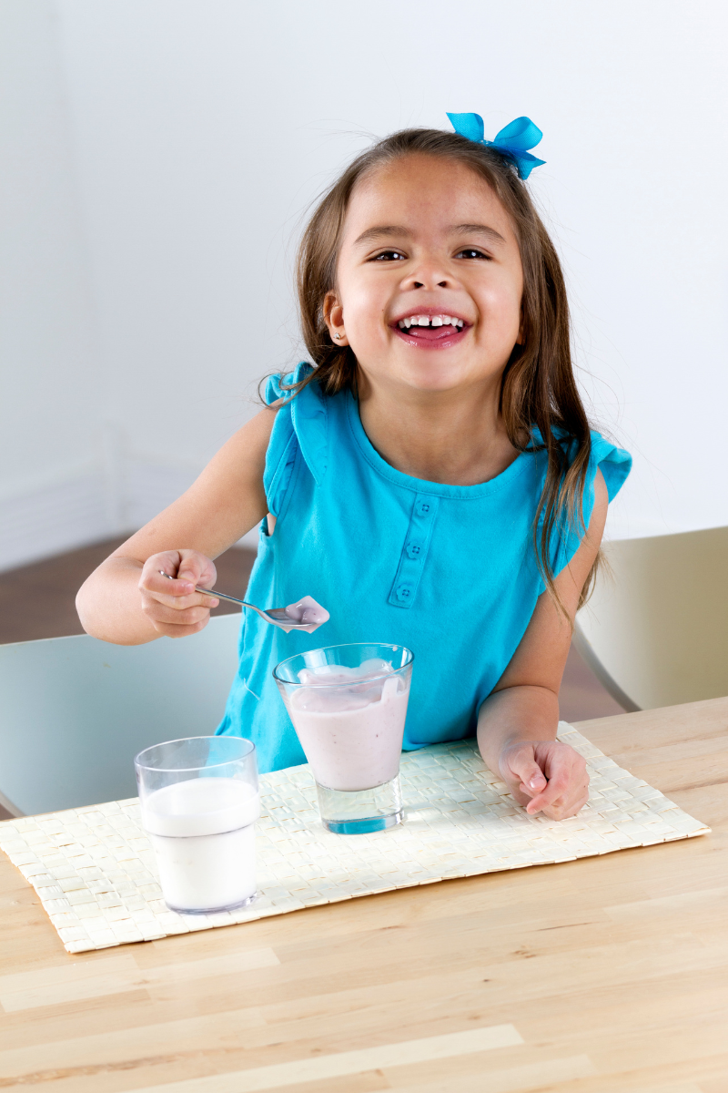 close up of a girl eating flavoured yogurt from a glass cup