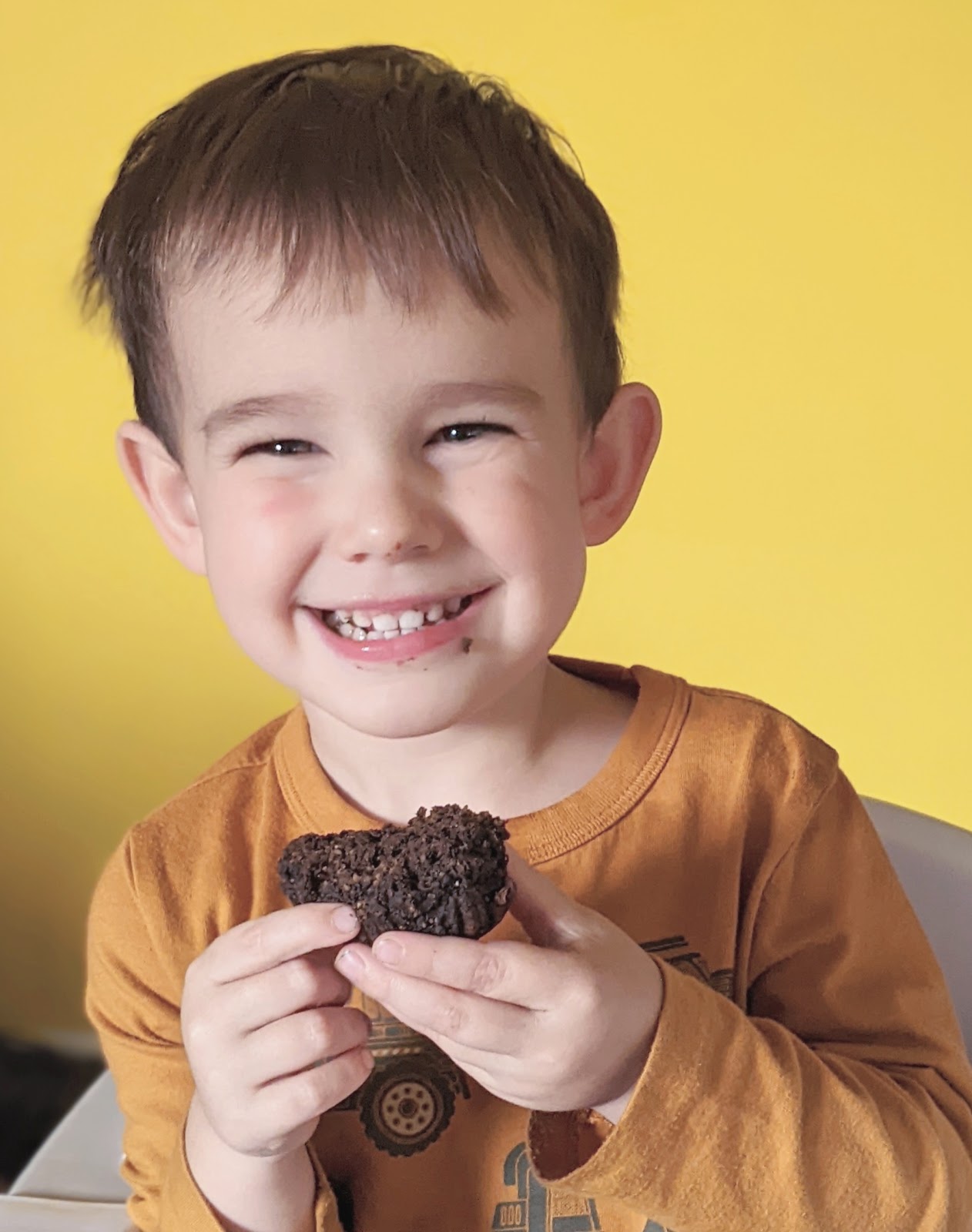 close up of a smiling boy eating chocolate pumpkin muffins