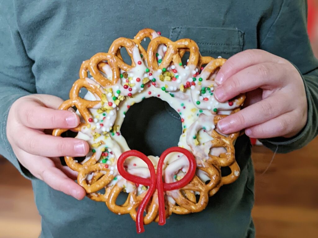 a child holding a white chocolate pretzel wreath
