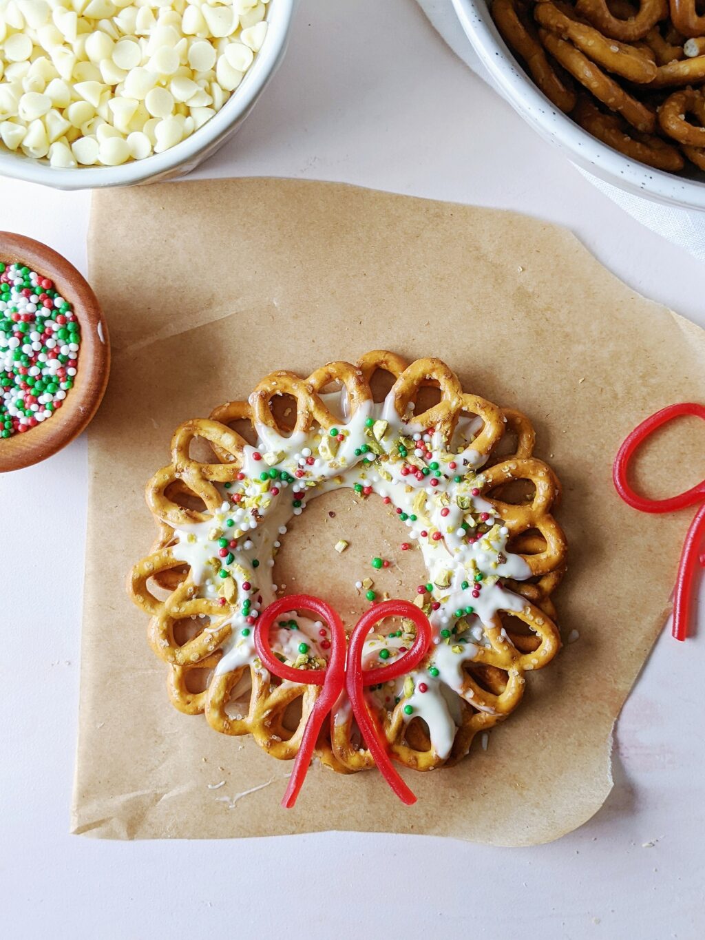 top down view of chocolate pretzel wreath with sprinkles and a candy bow on top