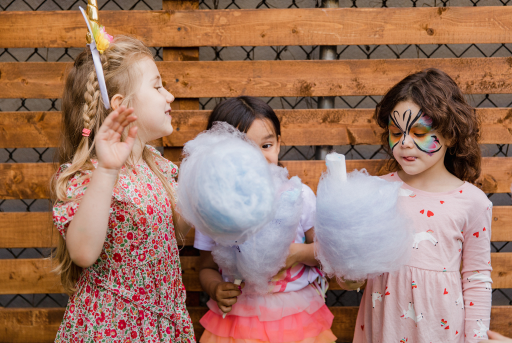 three cute kids at a party holding candy floss